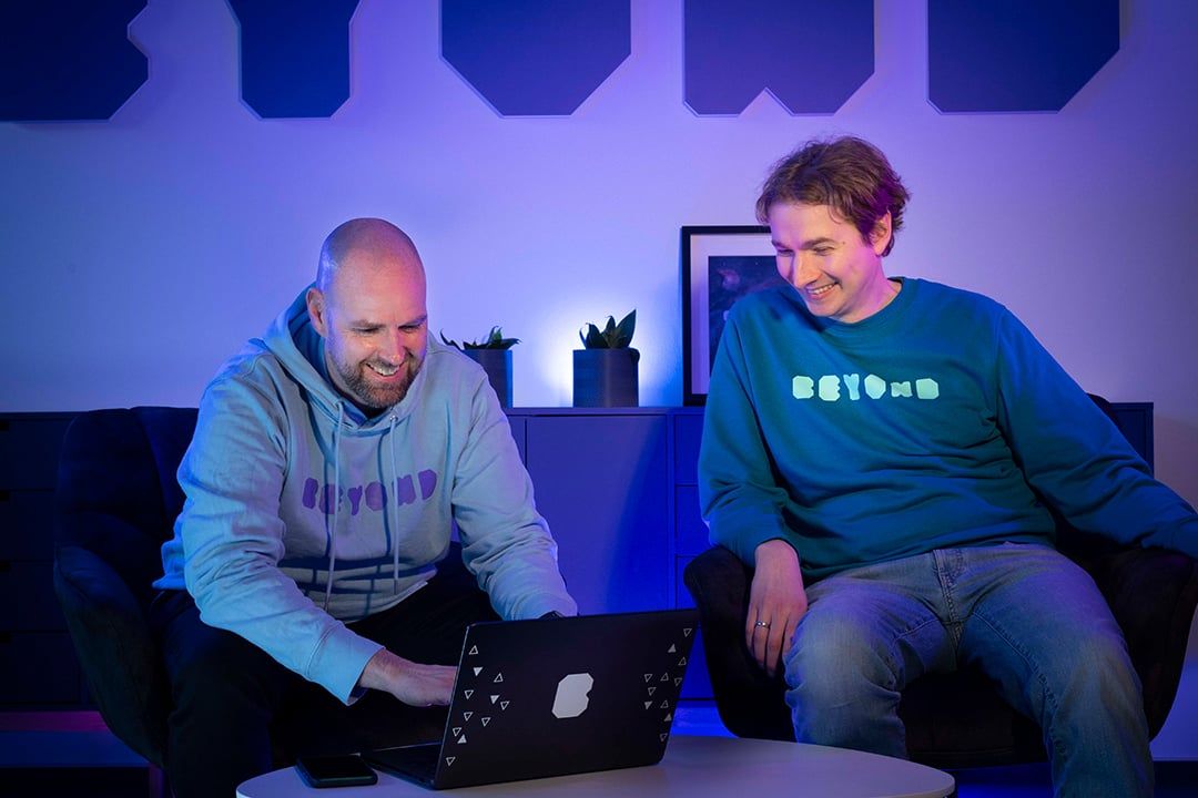 Two BEYONDIT colleagues talking over a laptop