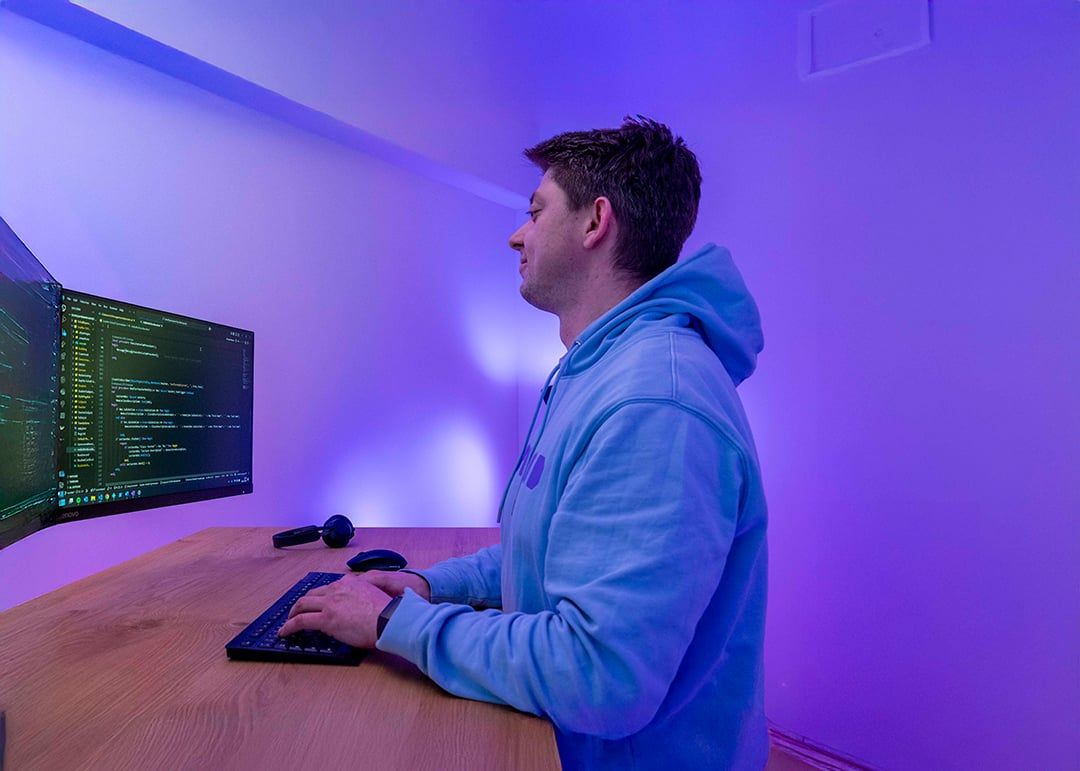 BEYONDIT developer working at a dual-monitor desk with source code on screen