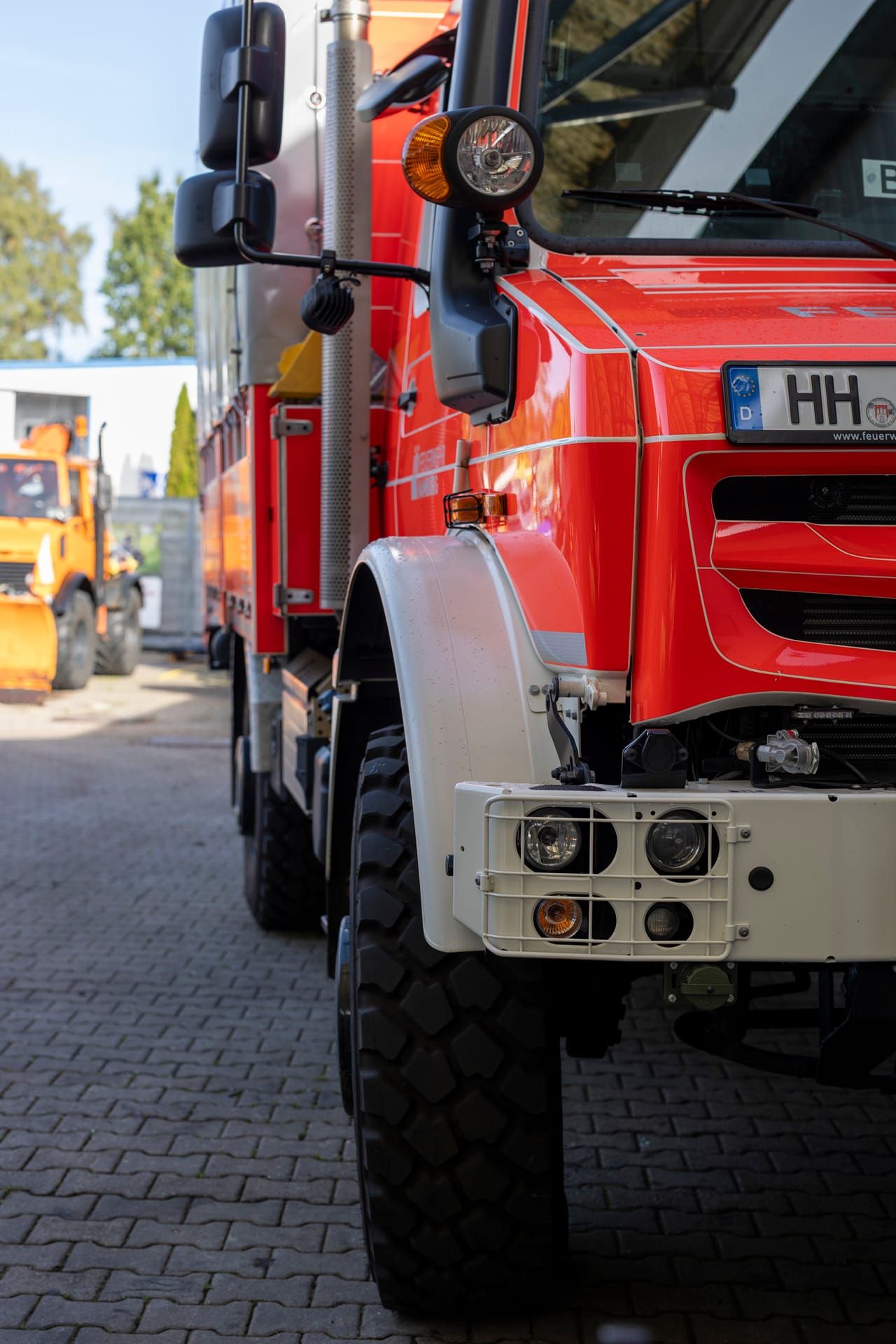 Red emergency vehicle in the yard, a winter service vehicle behind it