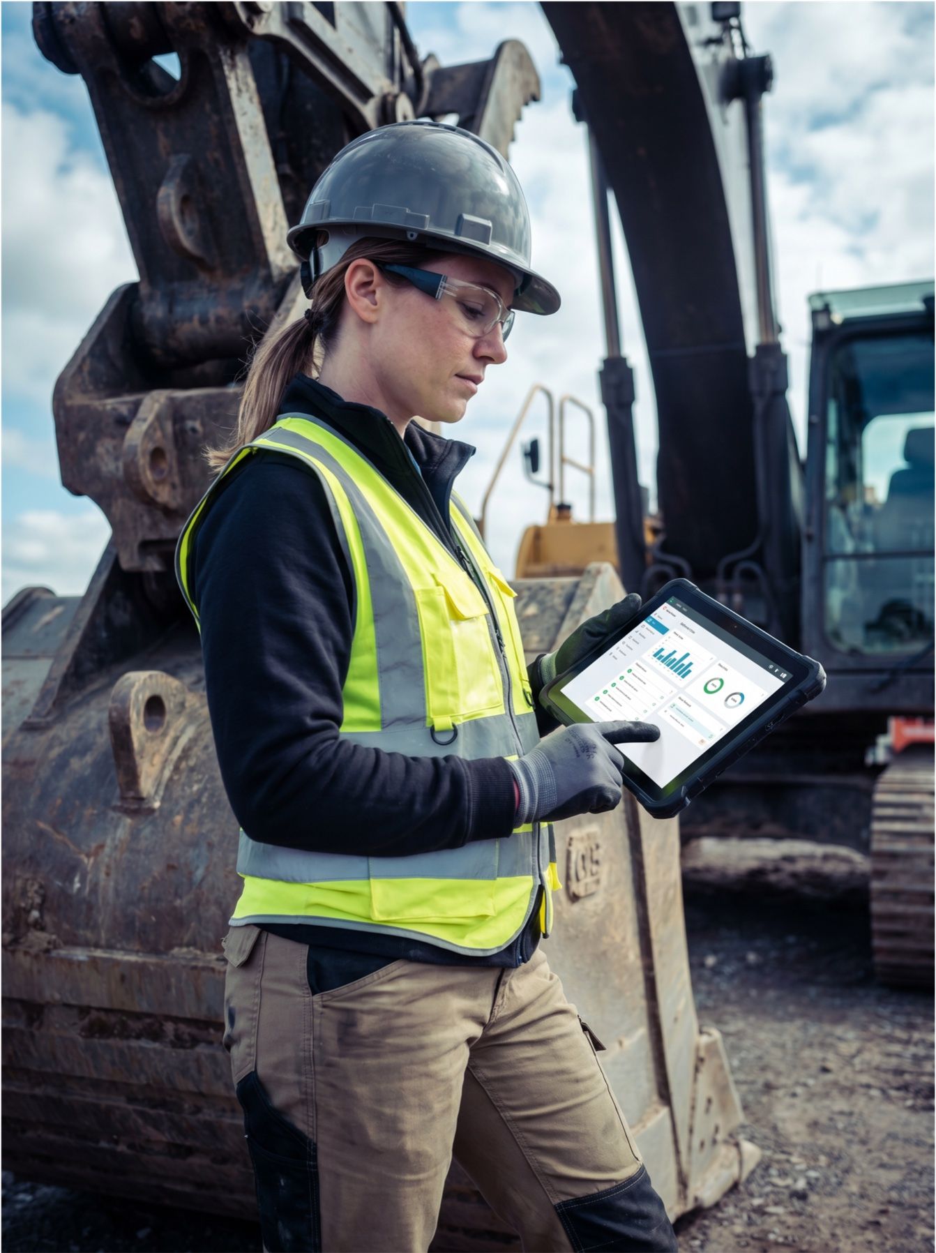 Servicetechnikerin am Bagger mit mobiler Service-App